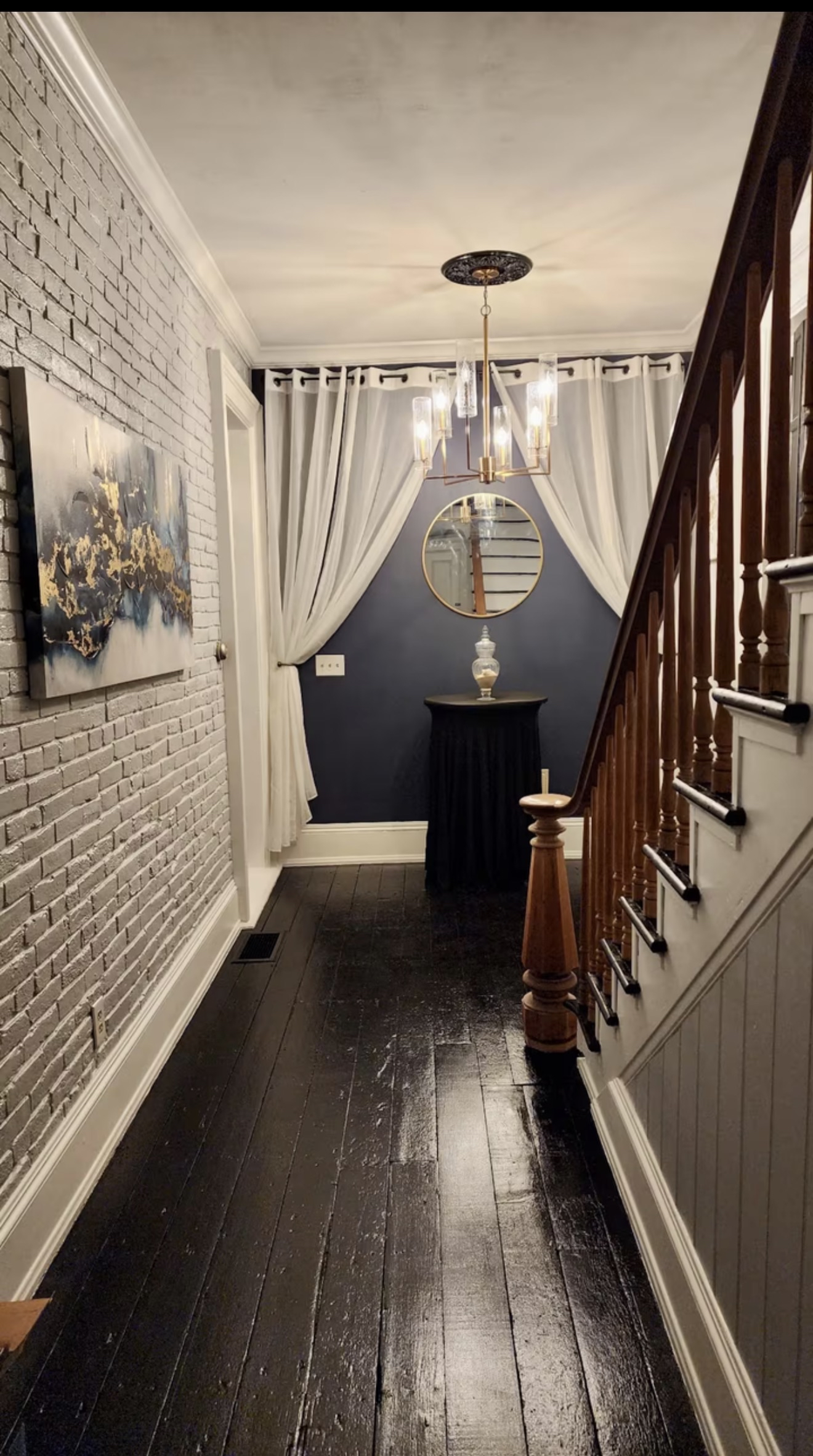 Grand hallway with exposed brick and chandelier